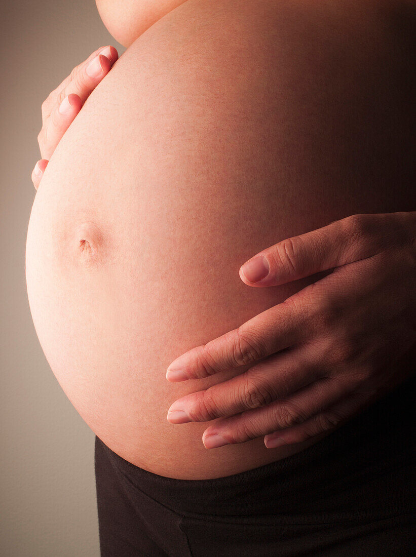 Mixed race woman holding pregnant stomach, New York, New York, United States