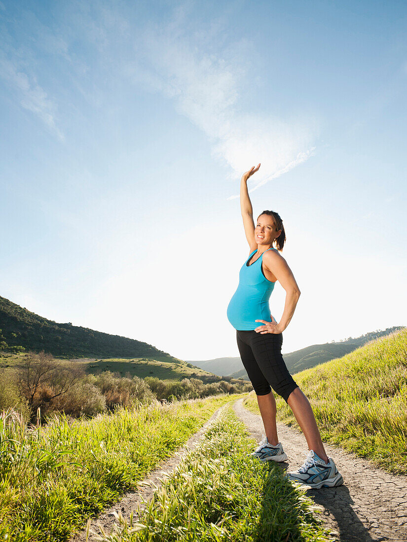 Schwangere hispanische Frau trainiert in abgelegenem Gebiet, Aliso Viejo, Kalifornien, USA