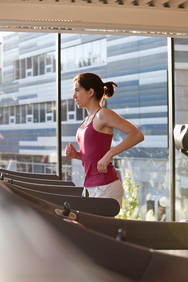 Woman running on treadmill in health club, Vancouver, BC, Canada