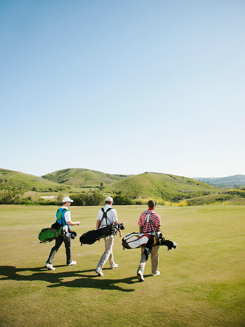 Men carrying golf bags on golf course, Mission Viejo, California, USA