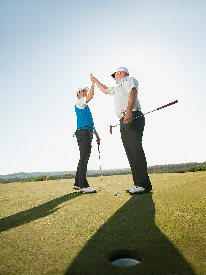 Caucasian golfers high fiving on golf course, Mission Viejo, California, USA