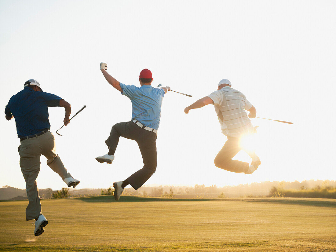 Excited golfers jumping in mid-air on golf course, Mission Viejo, California, USA