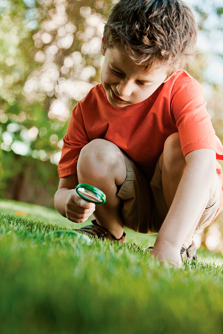Caucasian boy looking at grass with magnifying glass, Los Angeles, California, USA