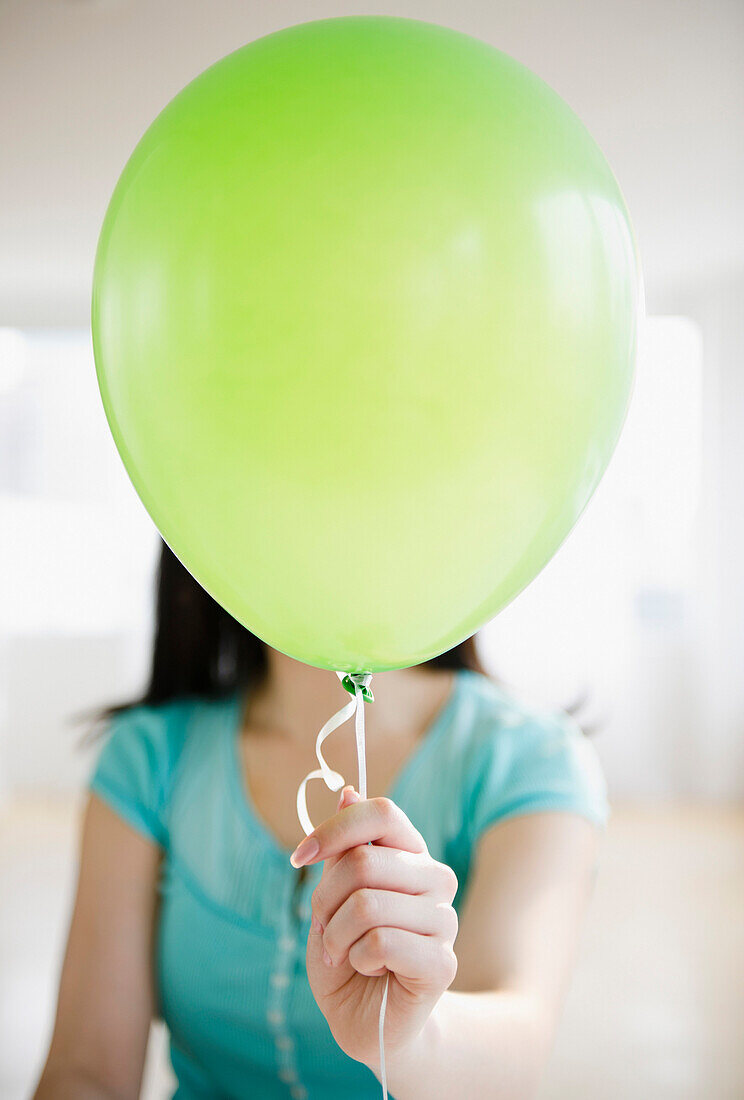 Korean woman holding balloon in front of her face, Jersey City, New Jersey, USA