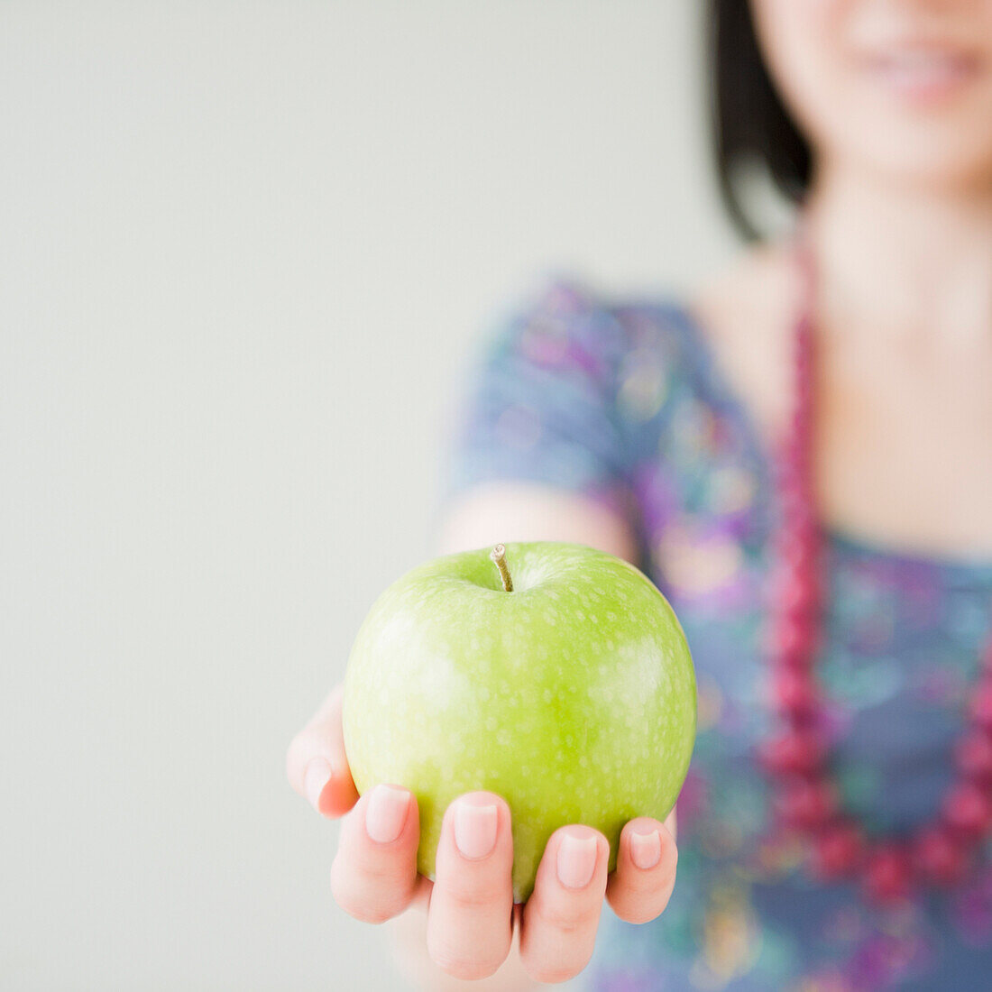 Korean woman holding green apple, Jersey City, New Jersey, USA