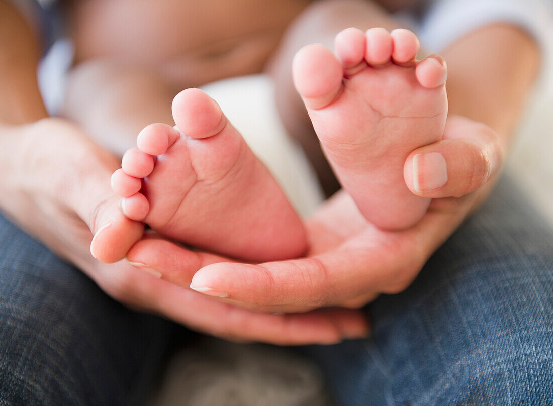 Close up of African American mother holding baby's feet, Jersey City, New Jersey, USA