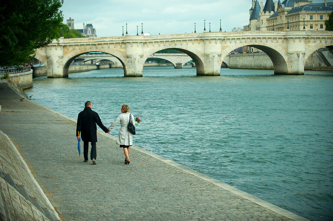 Caucasian couple holding hands and walking near river, Paris, Paris, France