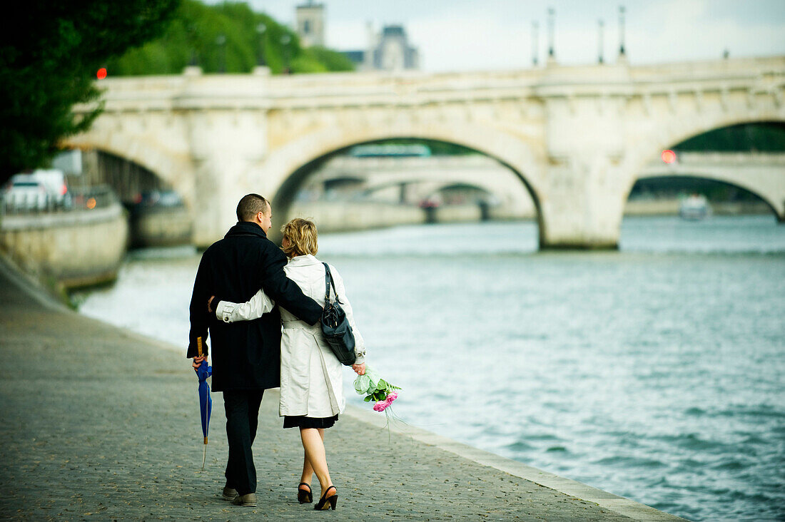 Caucasian couple hugging and walking near city river, Paris, Paris, France