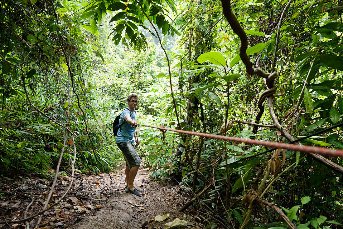 Caucasian man pulling rope in jungle, Rai Leh, Krabi, Thailand