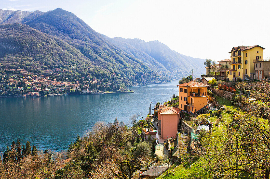 Houses on hillside next to remote lake, Carate Urio, Como, Italy