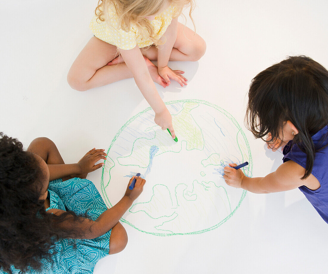 Girls sitting on floor drawing globe together, Jersey City, New Jersey, USA