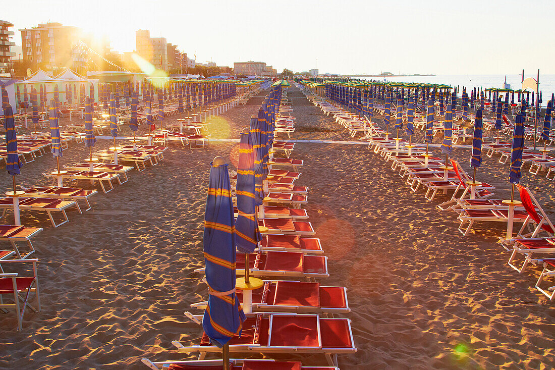 Umbrellas and beach chairs in a row on beach, Pesaro, Tuscany, Italy