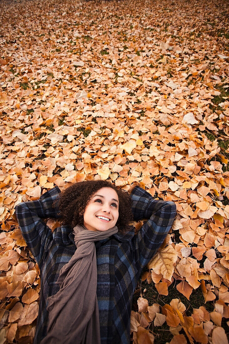 Caucasian woman laying in autumn leaves, Provo, Utah, USA