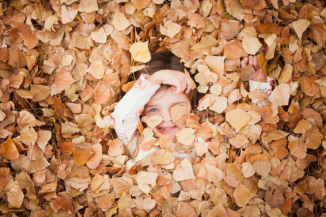 Caucasian girl laying in autumn leaves, Provo, Utah, USA