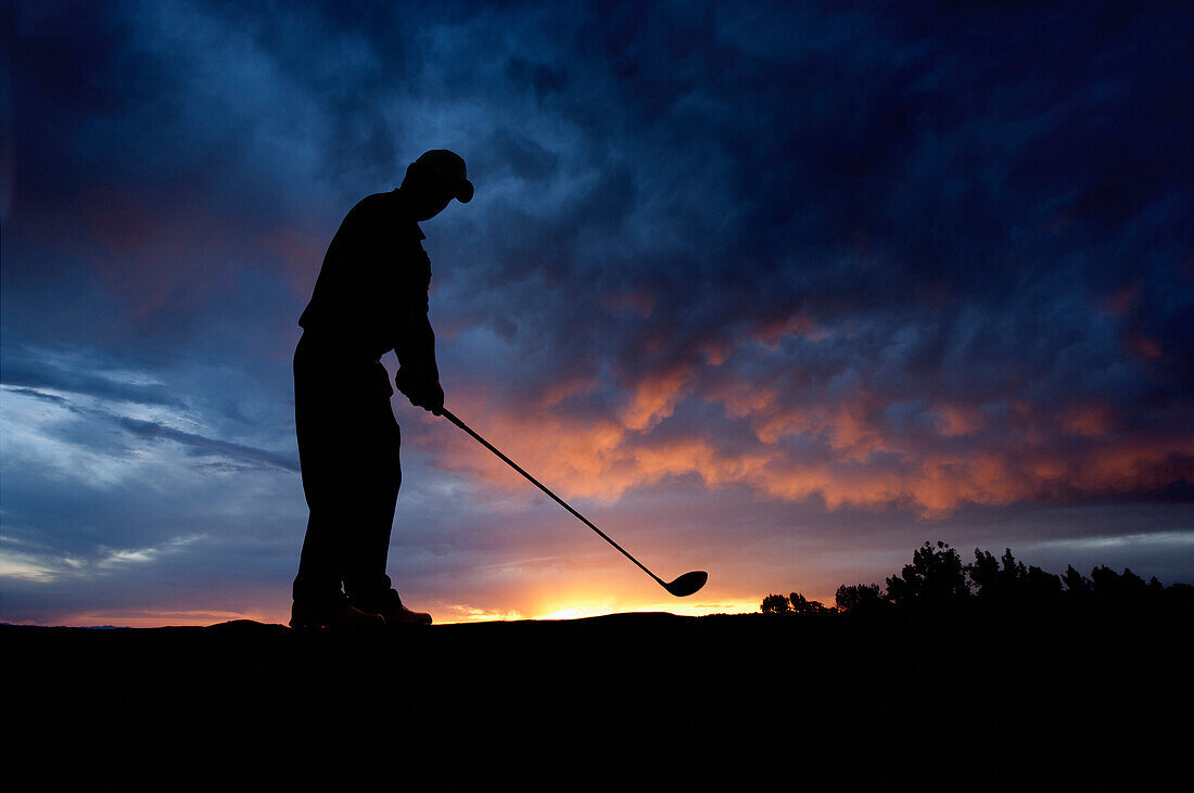 Caucasian golfer swinging golf club at sunset, Lehi, Utah, USA
