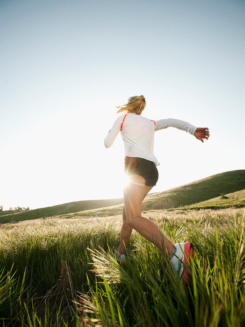 Caucasian woman running in remote field, Ladera Ranch, California, USA