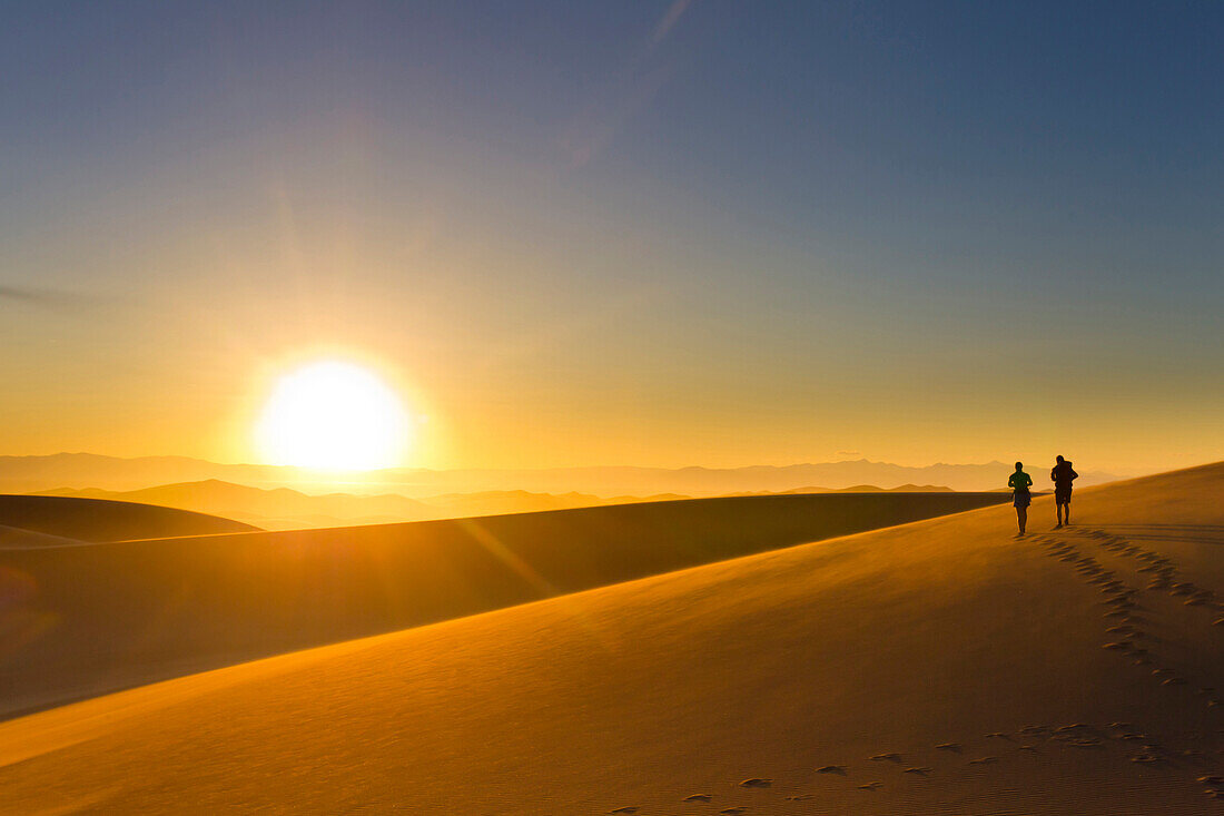 Hispanic couple walking on sand dune at sunset, Great Sand Dunes National Park, Colorado, USA