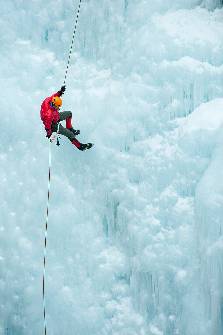 Caucasian man rappelling down ice wall, … – License image