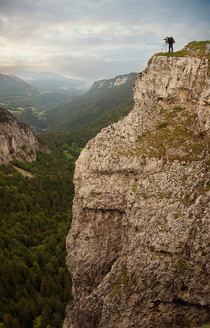 Caucasian man taking photographs from edge of cliff, Neuchatel, Neuchatel, Switzerland