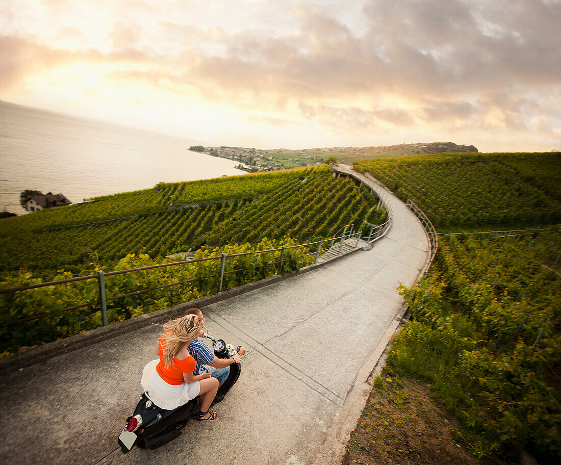 Couple riding scooter in vineyard, Epesses, Montreux, Switzerland