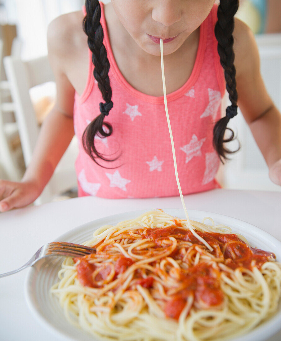 Mixed race girl eating spaghetti, Jersey City, New Jersey, USA