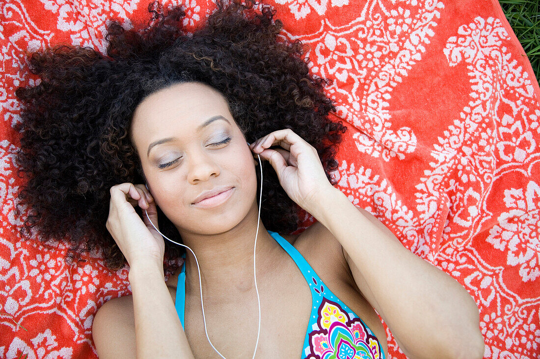 Hispanic woman laying on ground listening to music, Hull, Massachusetts, United States