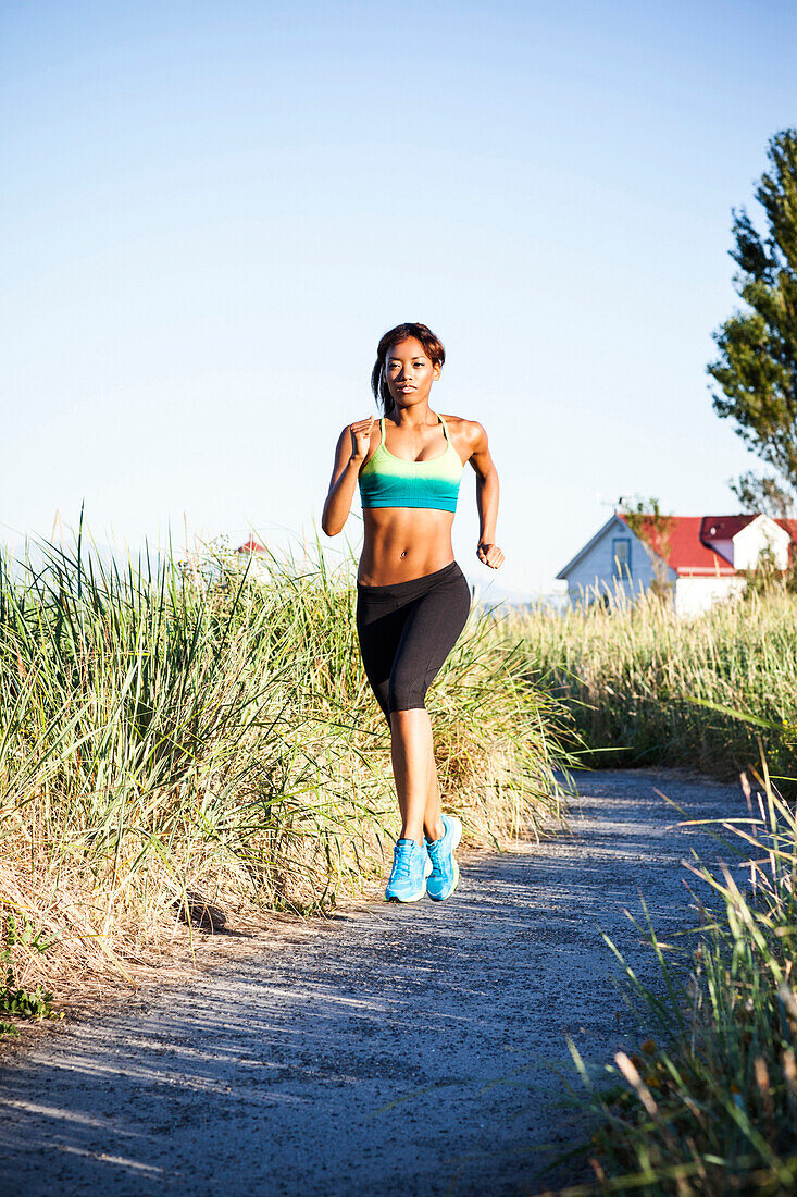 Mixed race woman running on dirt road, Seattle, WA, USA