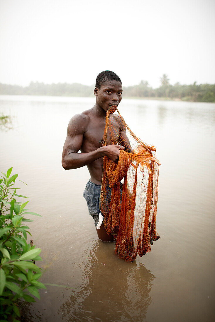 Young man fishing with cast net in river Mono, Agbanakin, near Grand-Popo, Mono Department, Benin