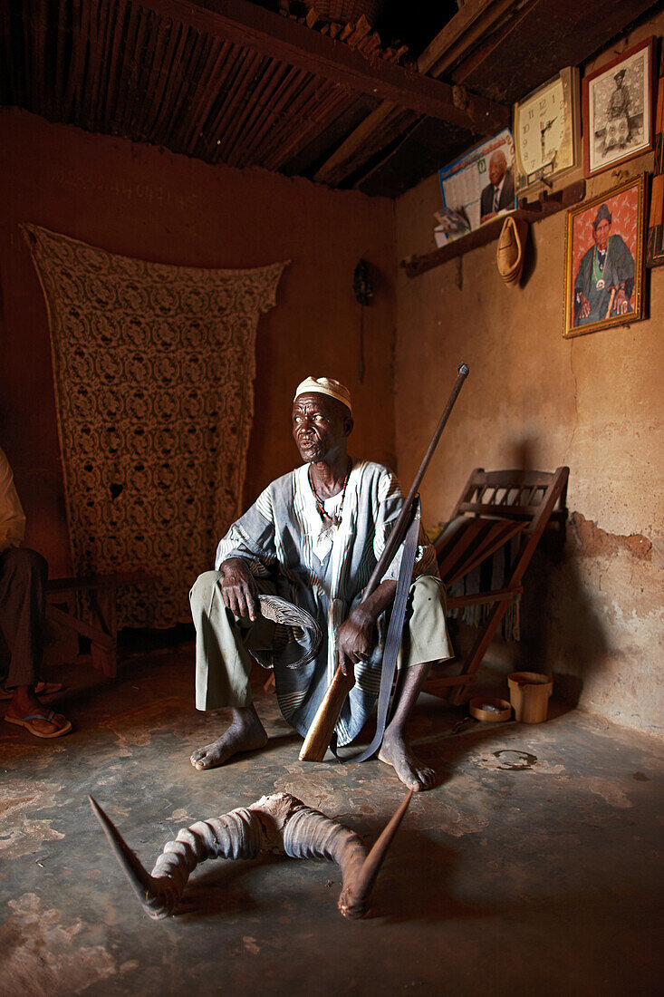Man with hunting trophies and family pictures, Bante, Collines Department, Benin