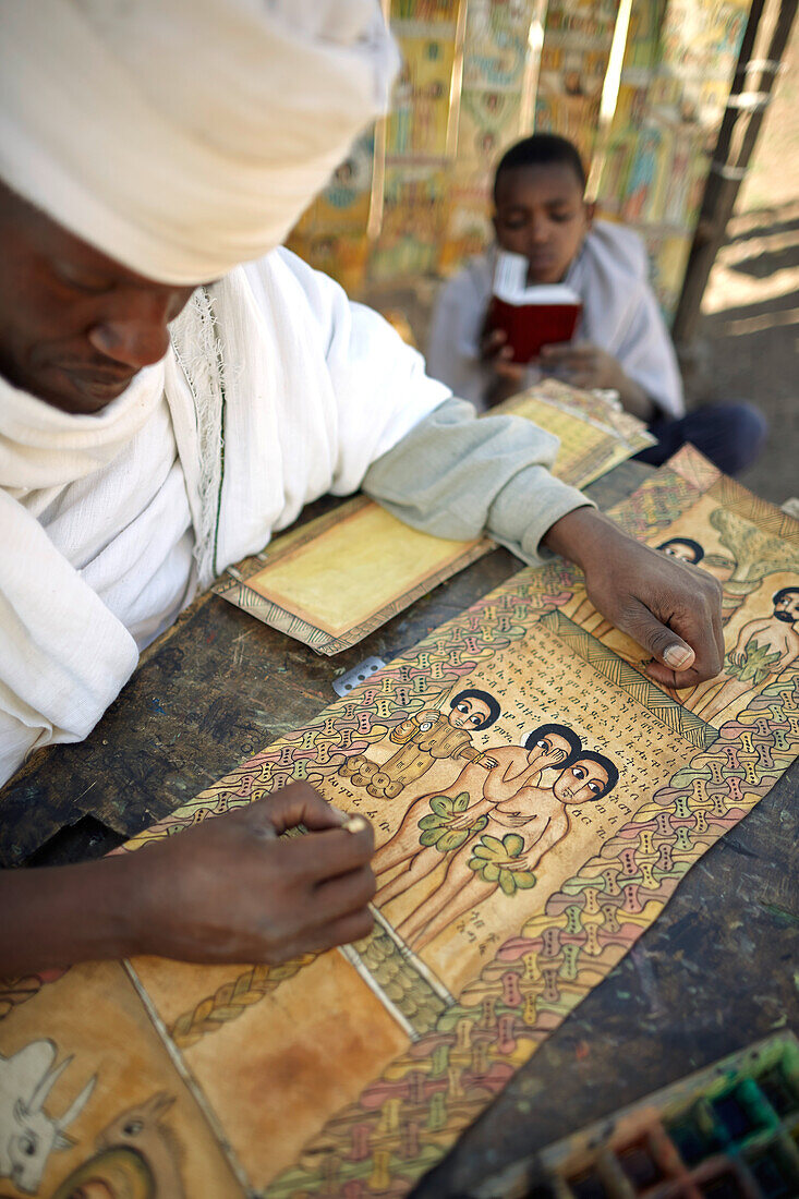 Priester Sine Tebeb malt und beschreibt biblische Szenen in Geez auf Ziegenhäute, bei Bet Giyorgis, St.-Georgs-Kirche, Lalibela, Amhara, Äthiopien