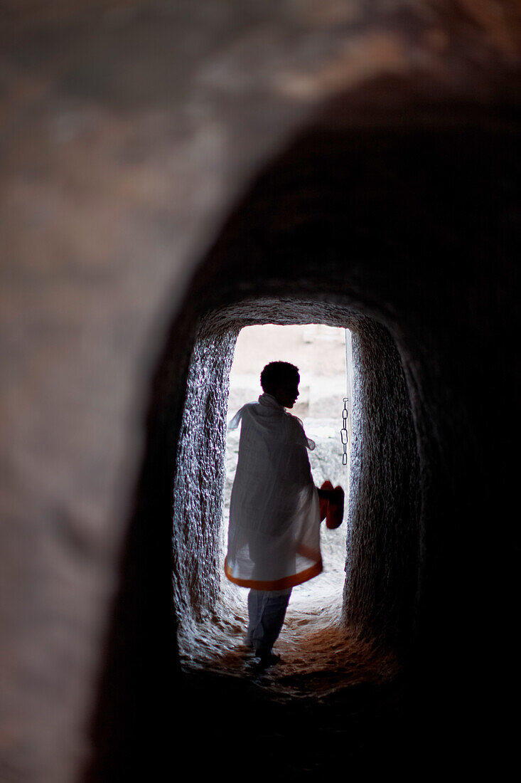 Man inside a rock tunnel at monolithic church Bete Medhane Alem, Church of St. George, Lalibela, Amhara region, Ethiopia