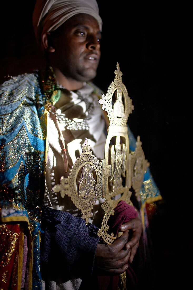 Priester Habtu hält ein Kirchenkreuz aus Gold, Grottenkirche Yemrehanna Krestos, Berg Abuna Yosef, Amhara, Äthiopien