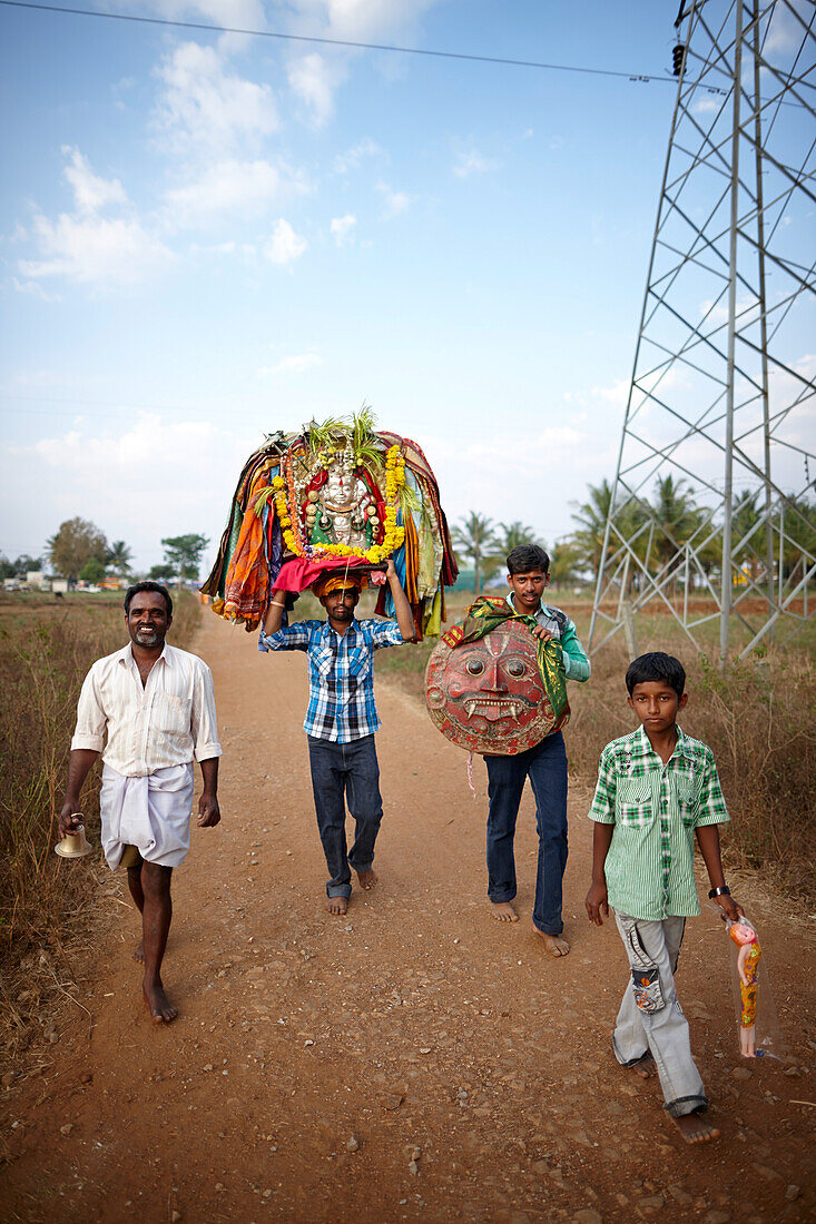 Männer tragen Gottesstatuen und Gottesmaske nach einer Prozession zurück, Angadehalli Belur, Karnataka, Indien