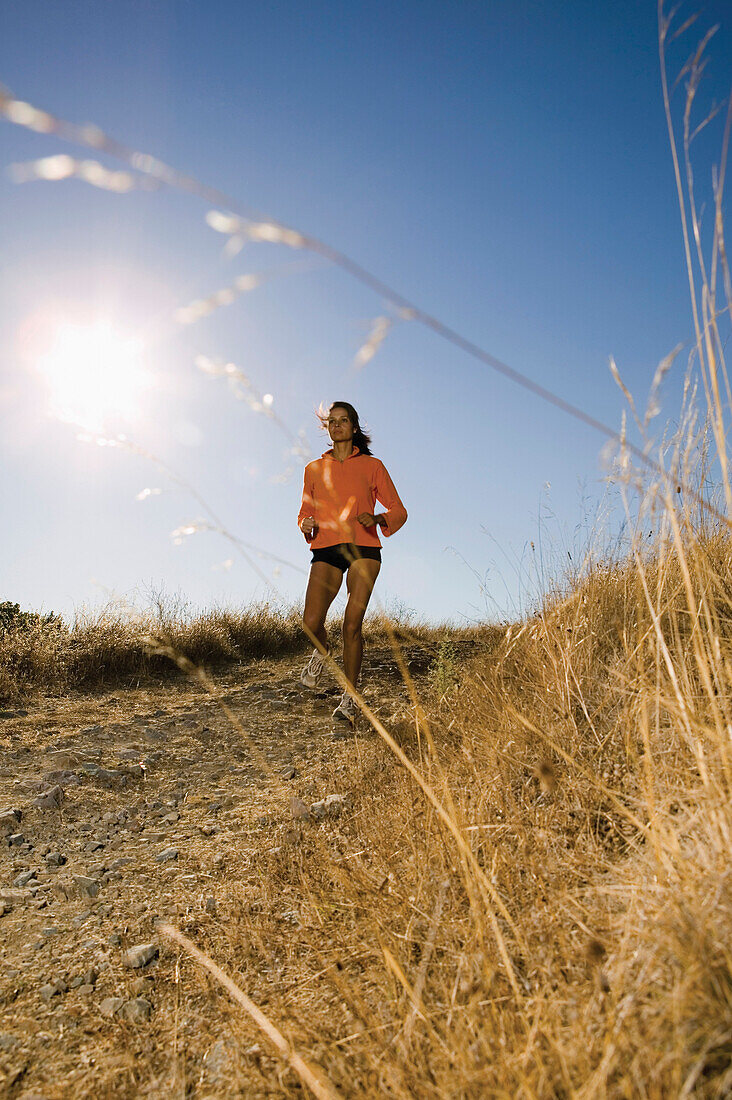 Full view of woman jogging on dirt road, San Rafael, CA