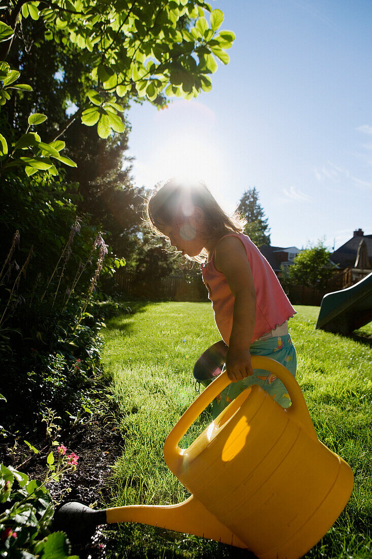Girl watering plants with watering can, Seattle, WA