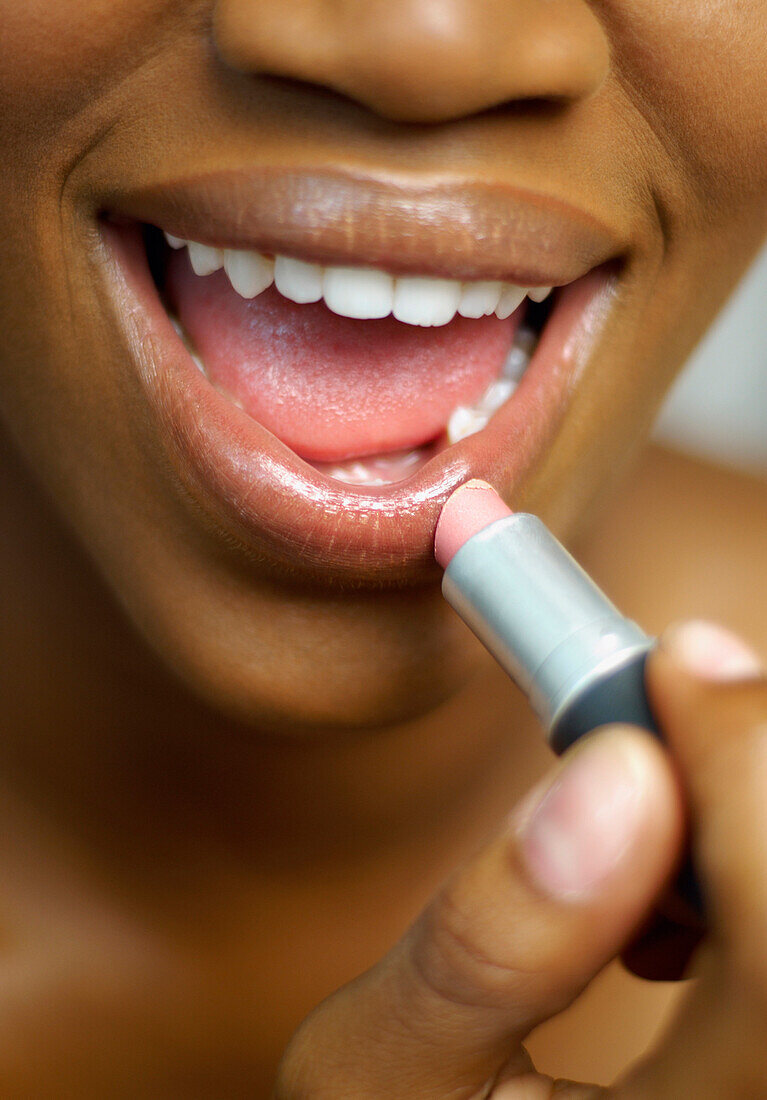Close up of African woman applying lipstick, Austin, TX