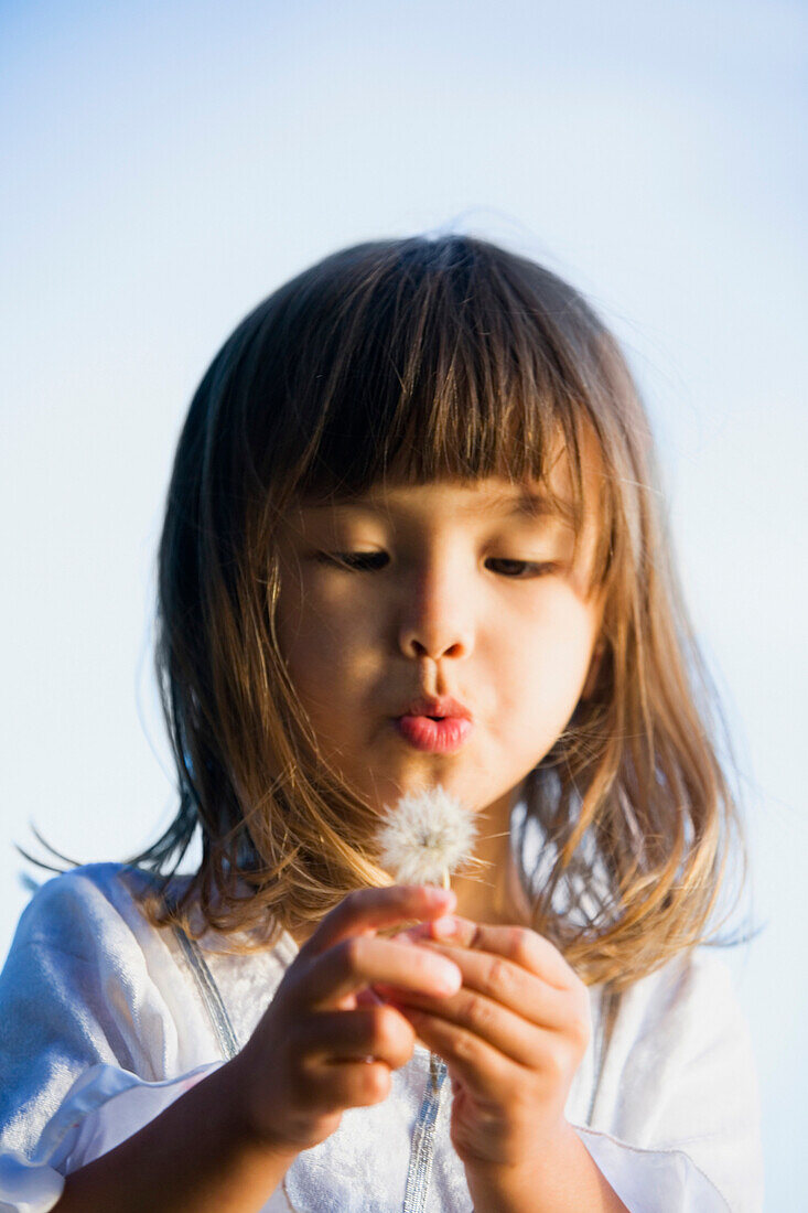 Asian girl blowing a dandelion, Bellingham, WA