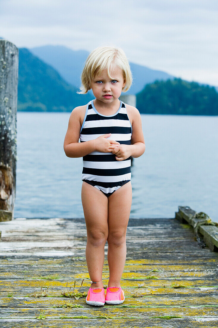 Young girl in bathing suit standing on wooden pier, Bellingham, WA