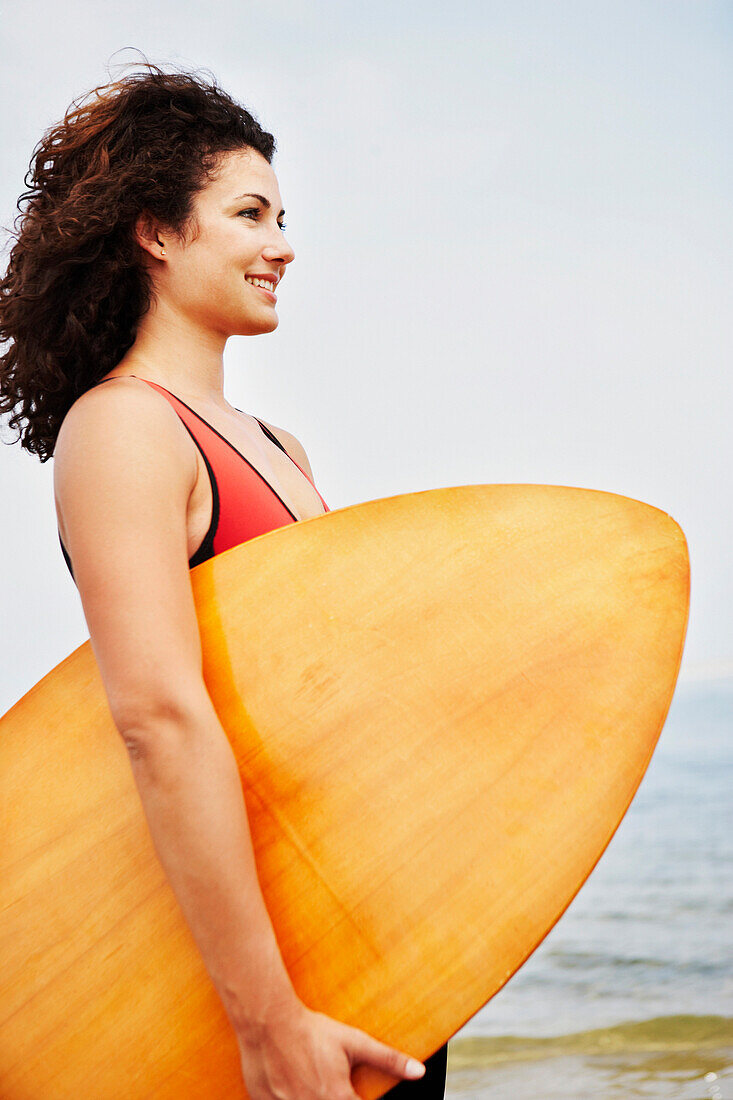 Young woman holding boogie board, Cape Cod, MA