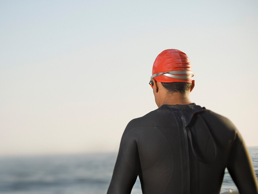 Rear view of Hispanic man wearing wetsuit, Newport Beach, CA