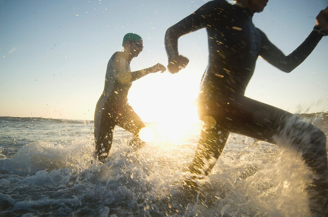 Multi-ethnic swimmers running in surf, Newport Beach, CA