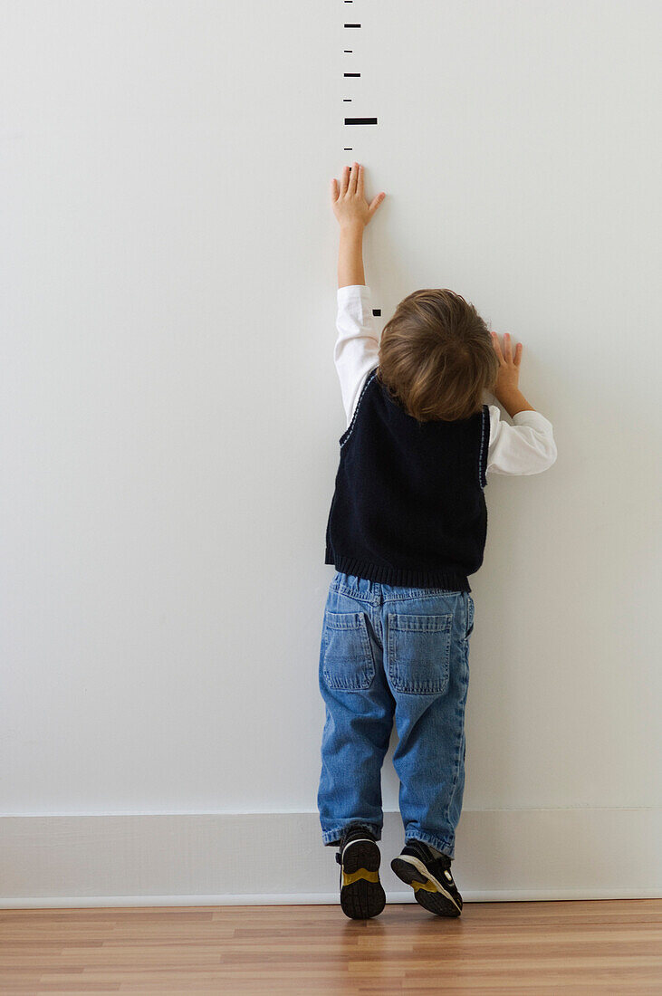 Boy reaching for height markers on wall, Richmond, VA