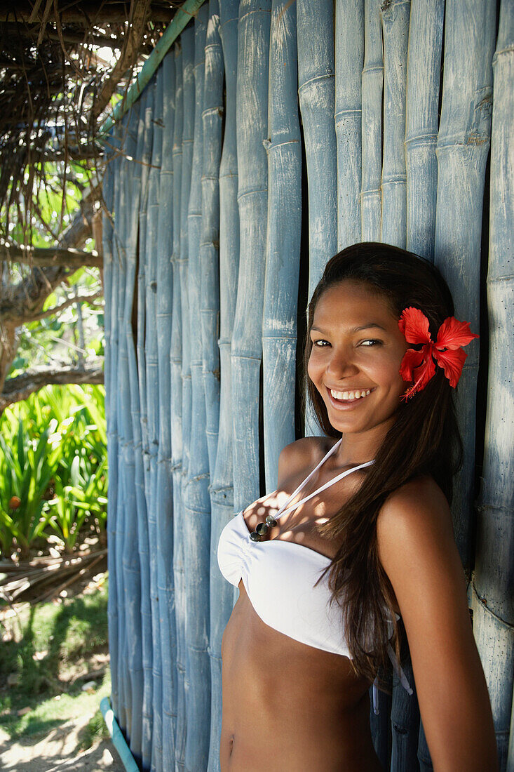 Hispanic woman in bikini leaning against bamboo, Carvao, Venezuela