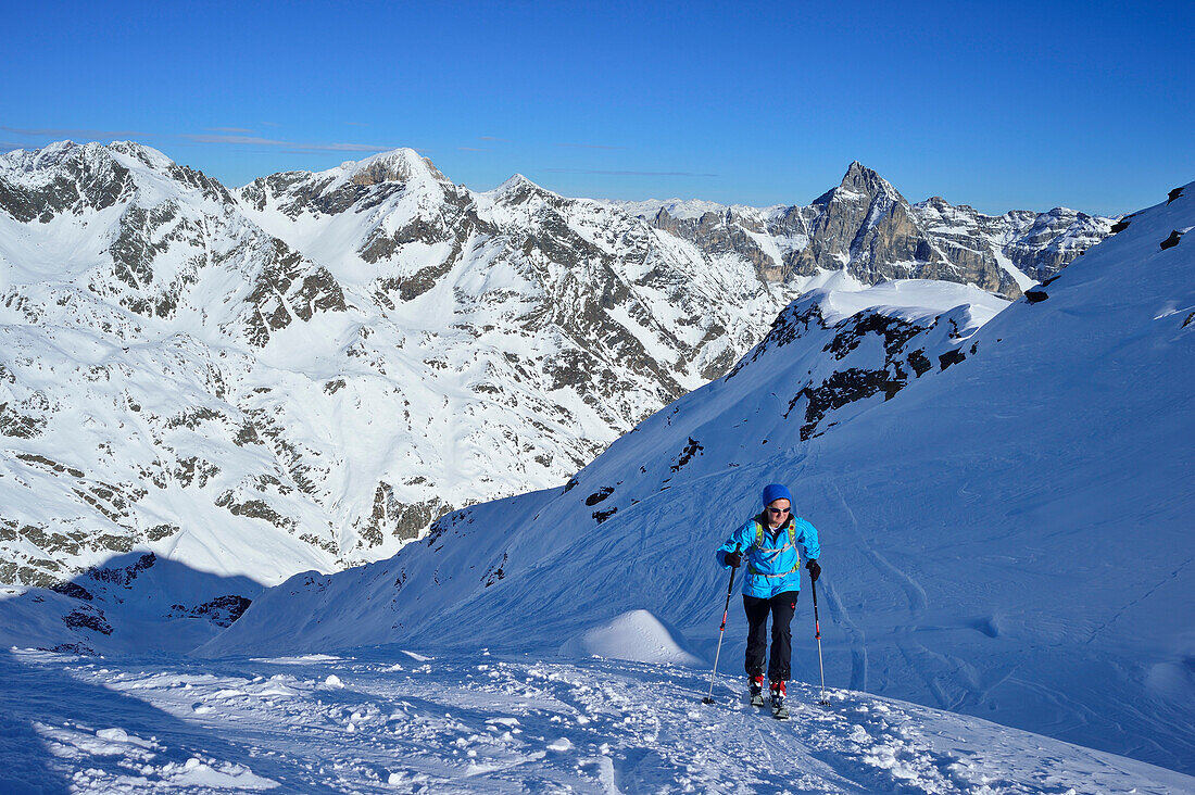 Frau auf Skitour steigt zum Äußeren Hocheck auf, Weißwand und Tribulaun im Hintergrund, Äußeres Hocheck, Pflerschtal, Stubaier Alpen, Südtirol, Italien