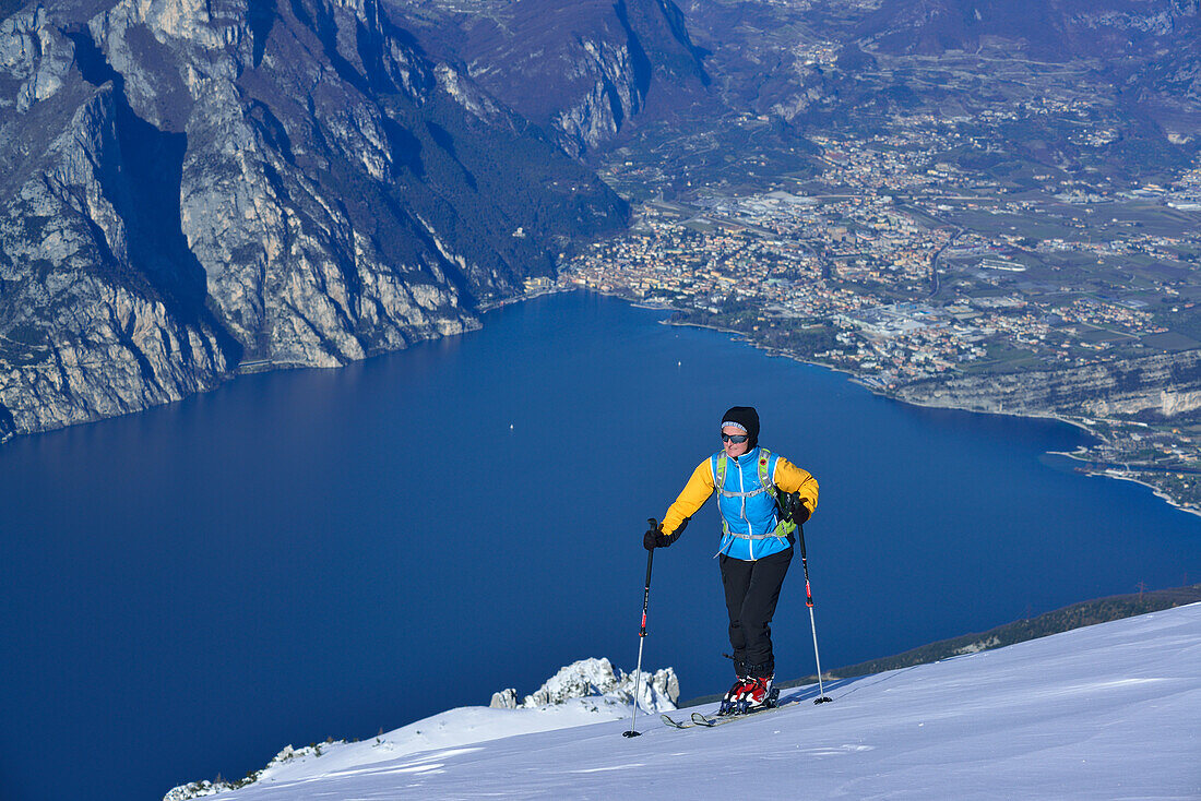 Female back-country skier ascending to Monte Baldo, lake Garda in background, Monte Baldo, Garda Mountains, Trentino, Italy