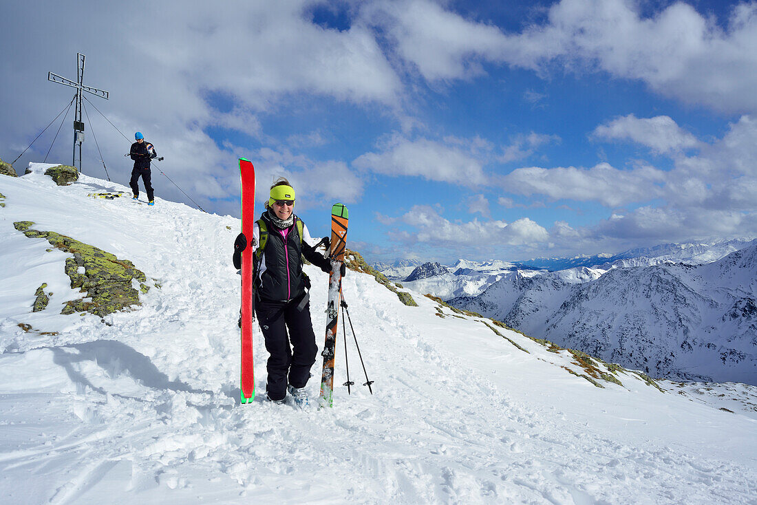 Two back-country skiers beside summit cross, Schafsiedel, Kitzbuehel Alps, Tyrol, Austria