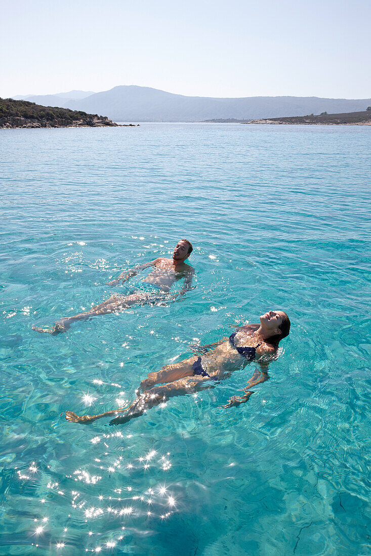 Couple swimming in Blue Lagoon, Vourvourou, Sithonia, Chalkidiki, Greece