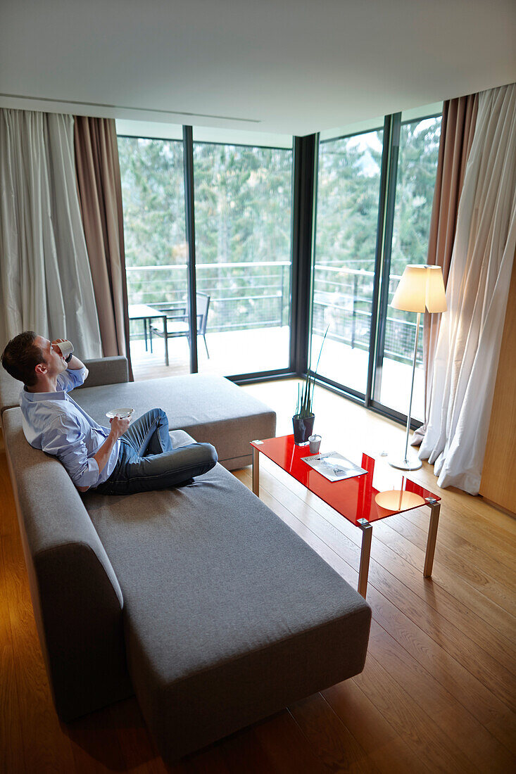 Man sitting on a sofa in a hotel suite, Baerenthal, Moselle, Lorraine, France