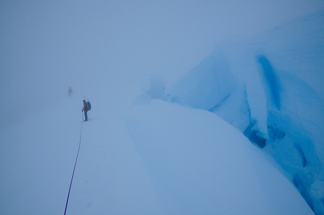 Two mountaineers in a whiteout on a glacier below Monte Sarmiento, Cordillera Darwin, Tierra del Fuego, Chile