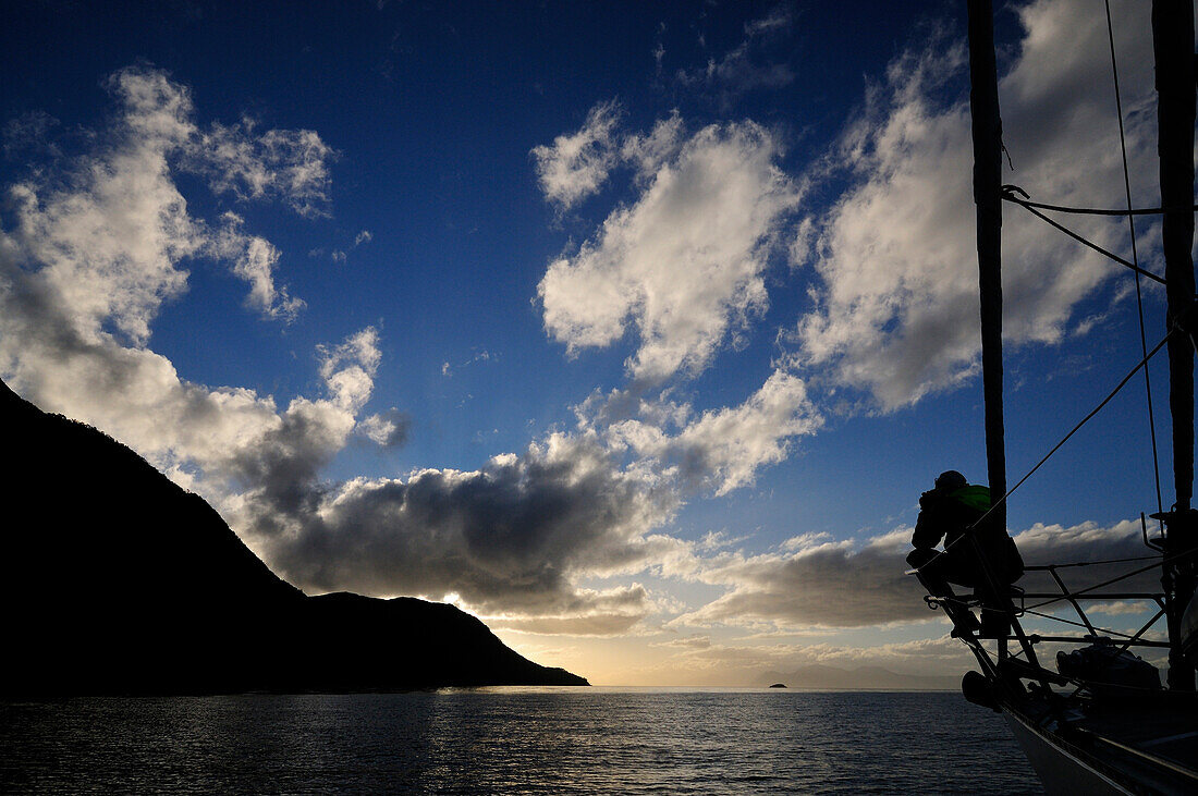 Man on a bow of a sailing boat, Cape Froward in background, Strait of Magellan, Chile